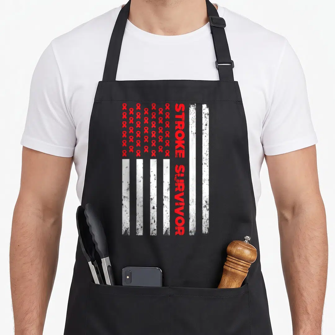 Stroke ribbon apron - Red ribbons and white vertical stripes with vertical STROKE SURVIVOR text in distressed style — shown on a black cotton canvas apron against a white background
