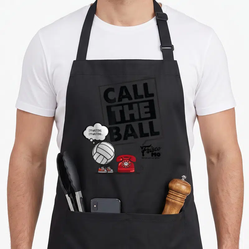 Call volleyball apron - Call The Ball text, red phone, cartoon volleyball with shoes, Frisco Mo logo — shown on a black cotton canvas apron against a white background