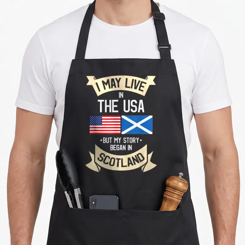 Scotland american flag apron - Stacked text with USA and Scottish flags on beige ribbons — shown on a black cotton canvas apron against a white background
