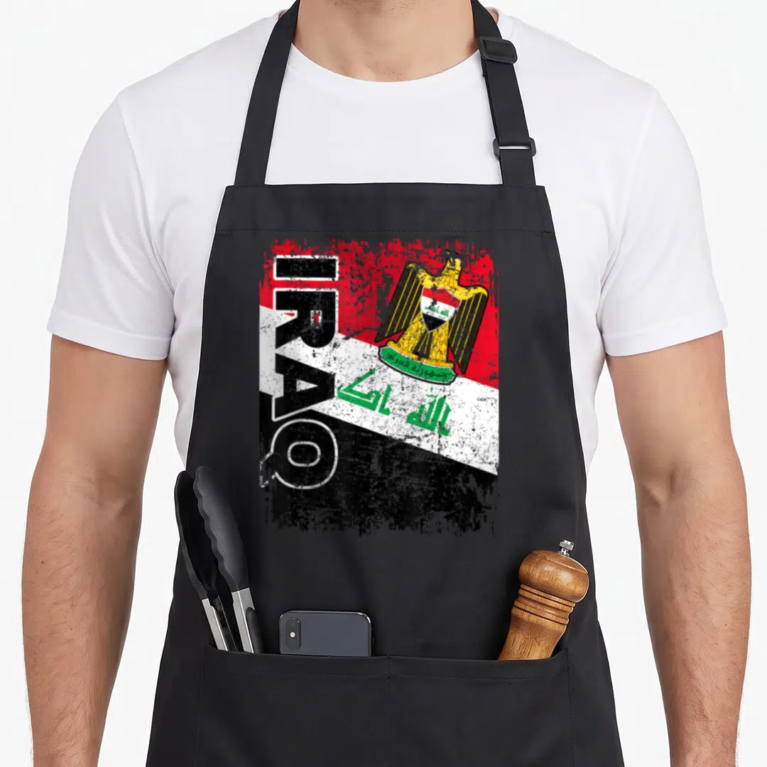Flag iraq apron - Vertical IRAQ text over distressed red white black flag with gold eagle and green Arabic script — shown on a black cotton canvas apron against a white background