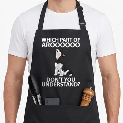 Siberian puppy husky apron - Cartoon dog sitting between white text Which Part of Arooooooo Don't You Understand — shown on a black cotton canvas apron against a white background