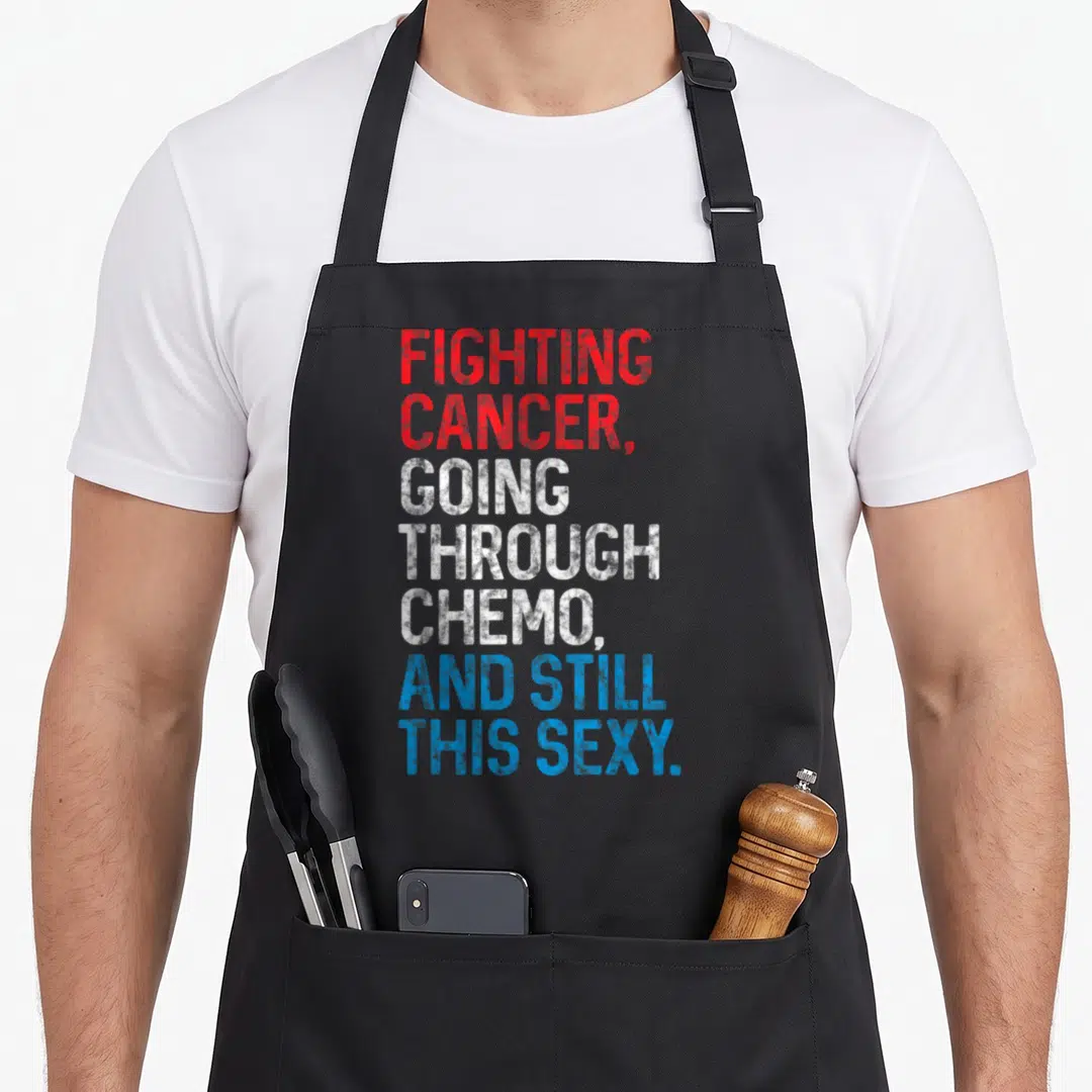 Cancer patient apron - Stacked red white and blue text reading Fighting Cancer Going Through Chemo And Still This Sexy — shown on a black cotton canvas apron against a white background