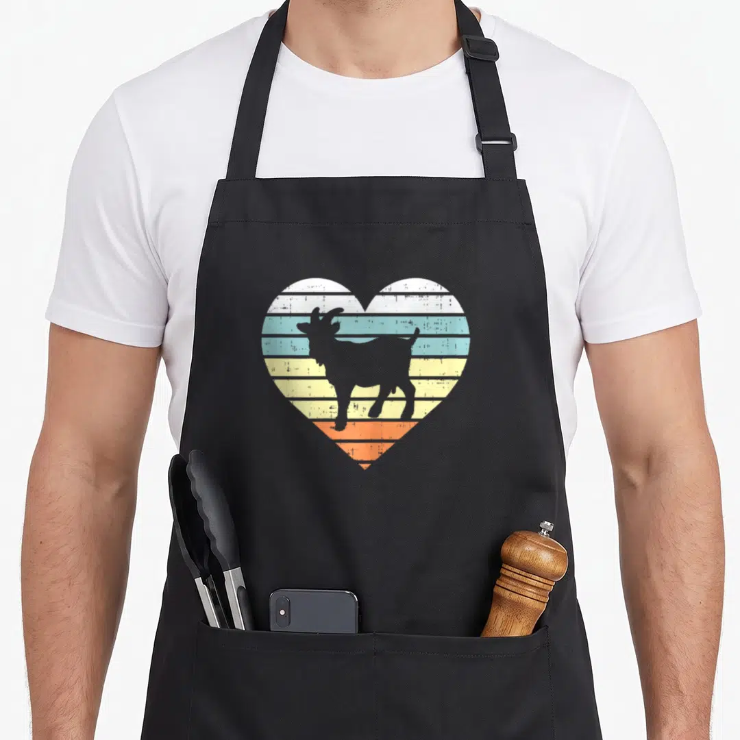 Country farmers apron - Retro goat silhouette inside striped heart in grey white blue yellow orange — shown on a black cotton canvas apron against a white background
