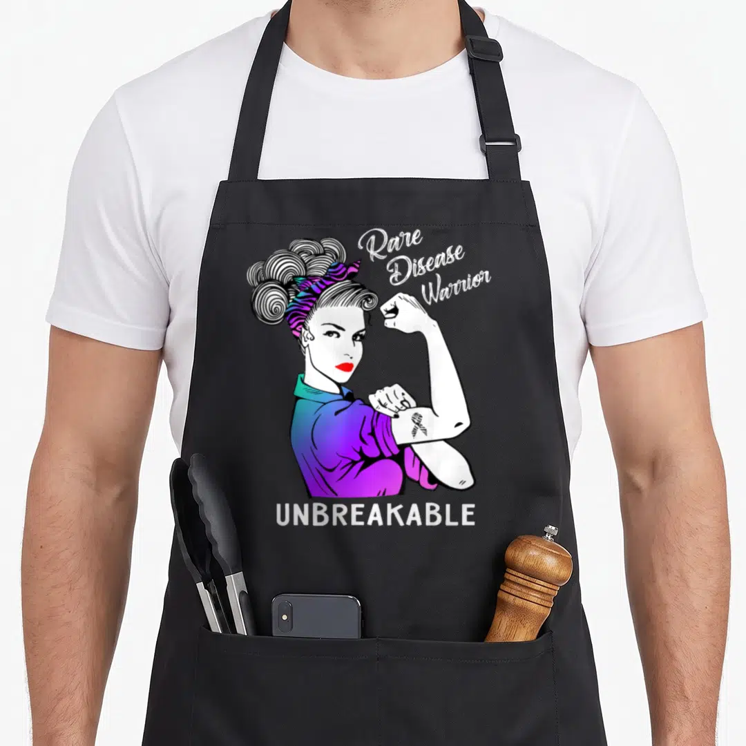 Rare warrior apron - Woman flexing arm with Rare Disease Warrior Unbreakable text and awareness ribbon tattoo — shown on a black cotton canvas apron against a white background