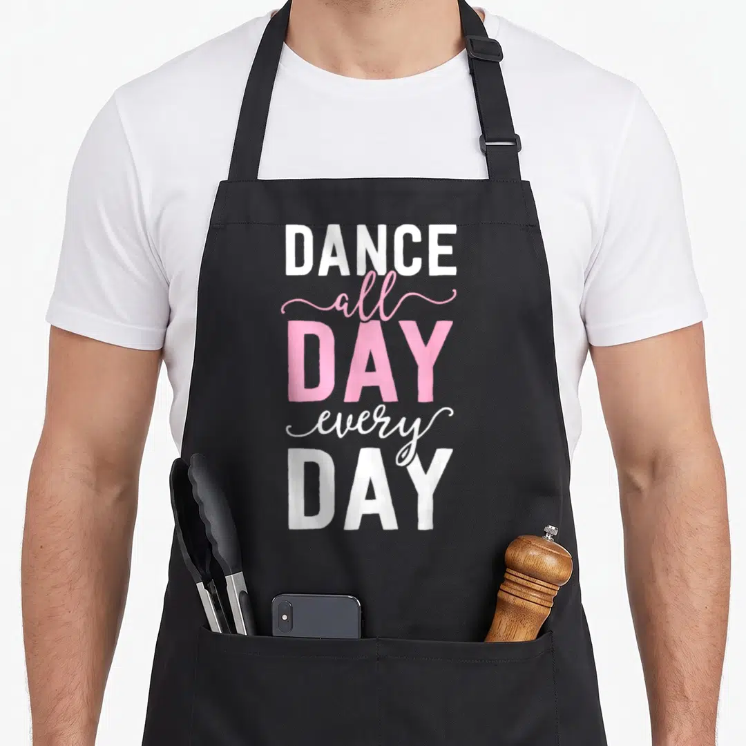 Cute ballet ballerina apron - DANCE all DAY every DAY text in white and pink stacked typography — shown on a black cotton canvas apron against a white background