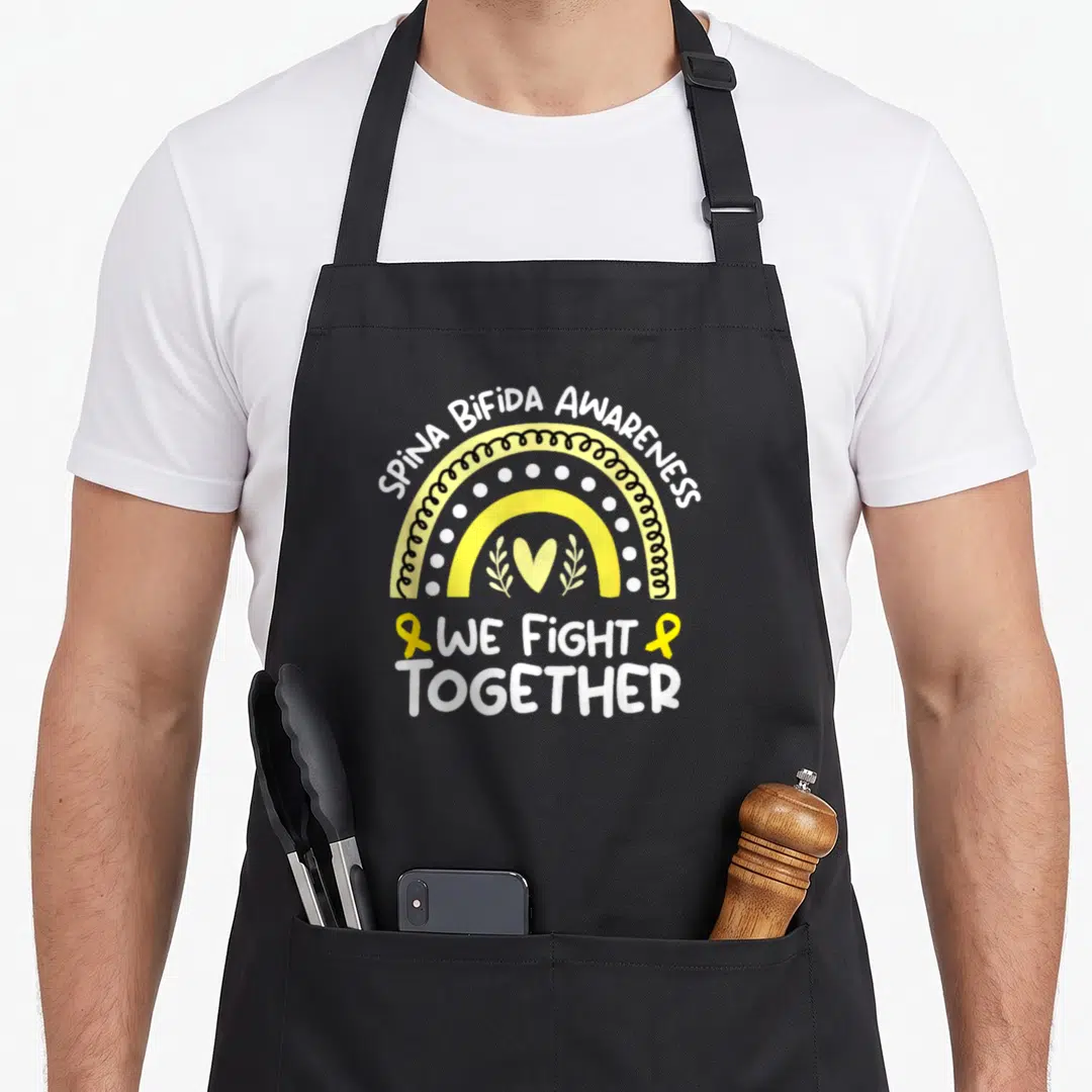 Fight spina bifida awareness apron - Yellow and white rainbow with heart leaves and WE FIGHT TOGETHER text — shown on a black cotton canvas apron against a white background
