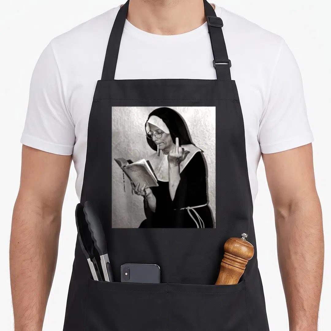 Nun attitude aprons - Black and white photo of a nun smoking and holding a Holy Bible while raising a middle finger — shown on a black cotton canvas apron against a white background