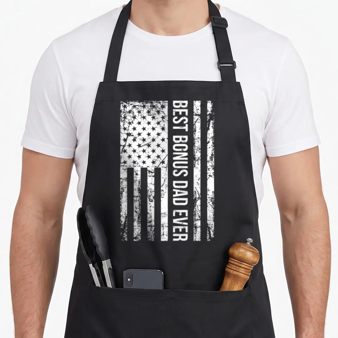 Step american flag apron - Vertical BEST BONUS DAD EVER text over distressed white USA flag stripes and stars — shown on a black cotton canvas apron against a white background