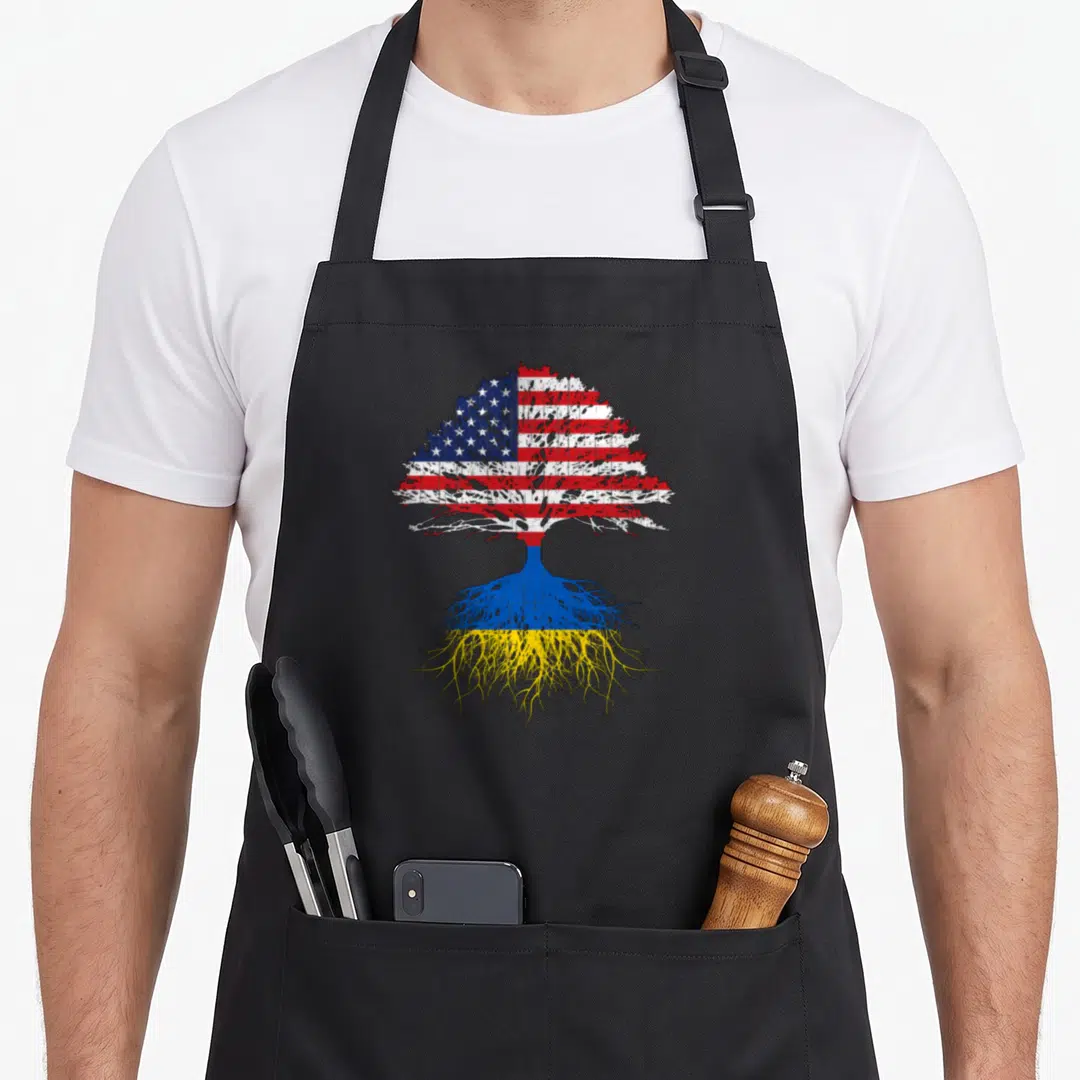 Root ukrainian aprons - Realistic tree with US flag leaves and Ukrainian flag roots in red white blue yellow — shown on a black cotton canvas apron against a white background