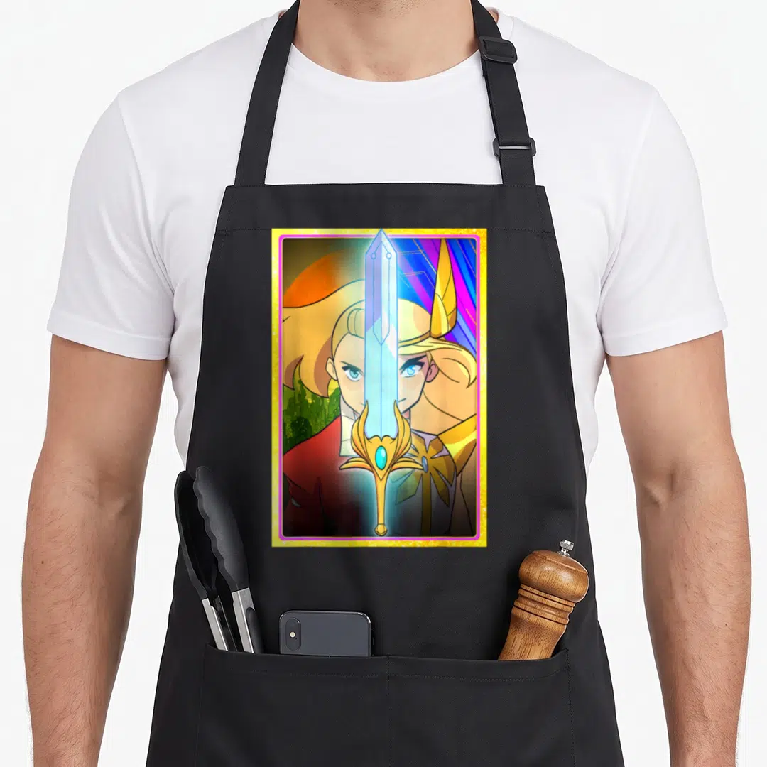 Adora split apron - Cartoon sword splits woman's face with gold blue red yellow glittery frame — shown on a black cotton canvas apron against a white background