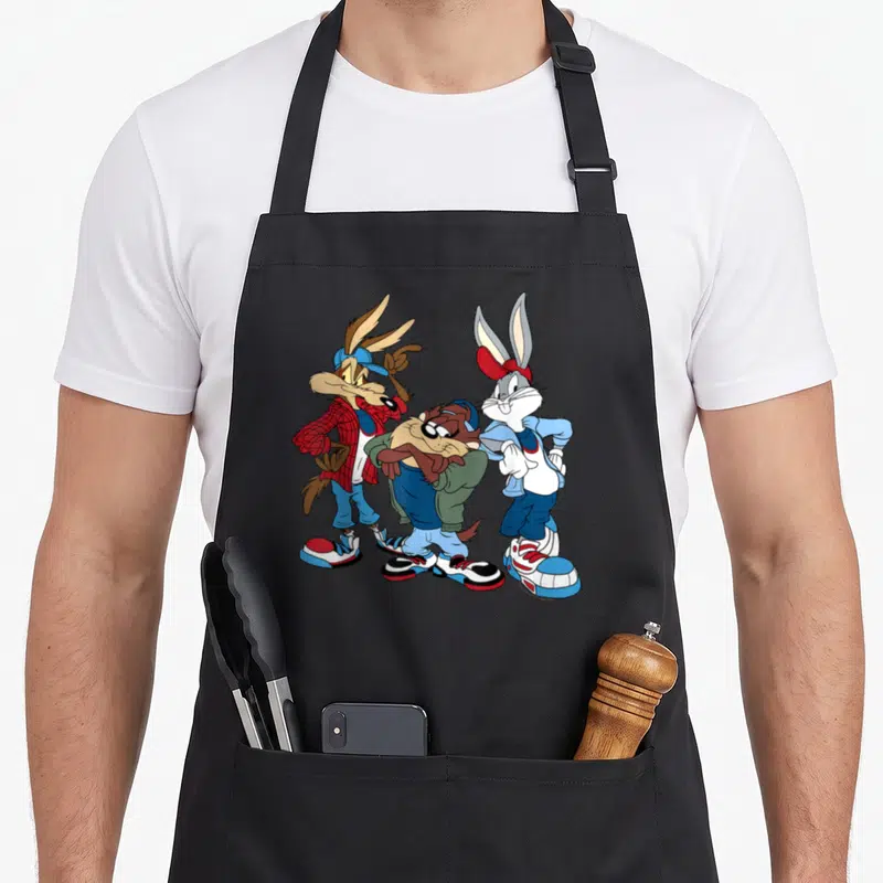 Wiley looney tune apron - Three cartoon characters in red and blue streetwear standing side-by-side — shown on a black cotton canvas apron against a white background