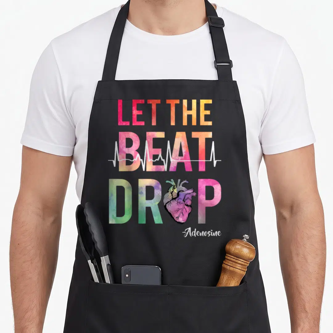 Beat nurse apron - Watercolor Let The Beat Drop Adenosine text with anatomical heart and ECG line crossing through BEAT — shown on a black cotton canvas apron against a white background