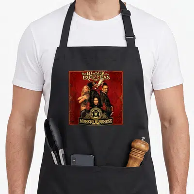 Eyed business apron - Four band members in red frame with gold Monkey Business banner and monkey emblem — shown on a black cotton canvas apron against a white background