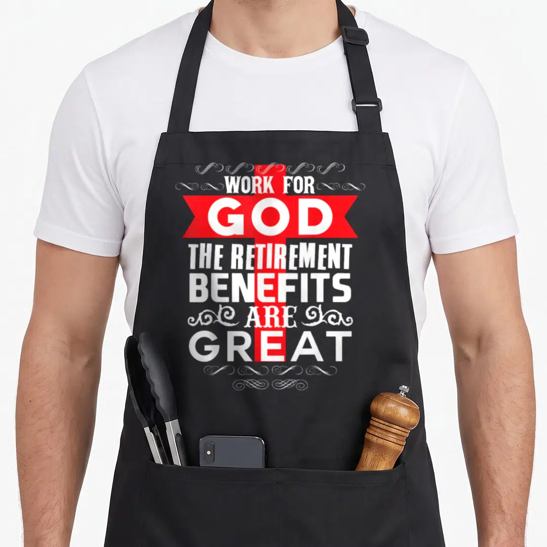 Benefit retirement apron - Red cross and ribbon with white text reading Work For God The Retirement Benefits Are Great — shown on a black cotton canvas apron against a white background