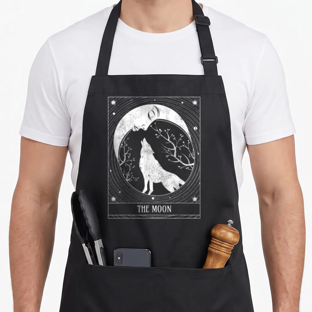 Crescent distressed apron - White line art wolf under moon with branches and stars in rectangular border with text — shown on a black cotton canvas apron against a white background