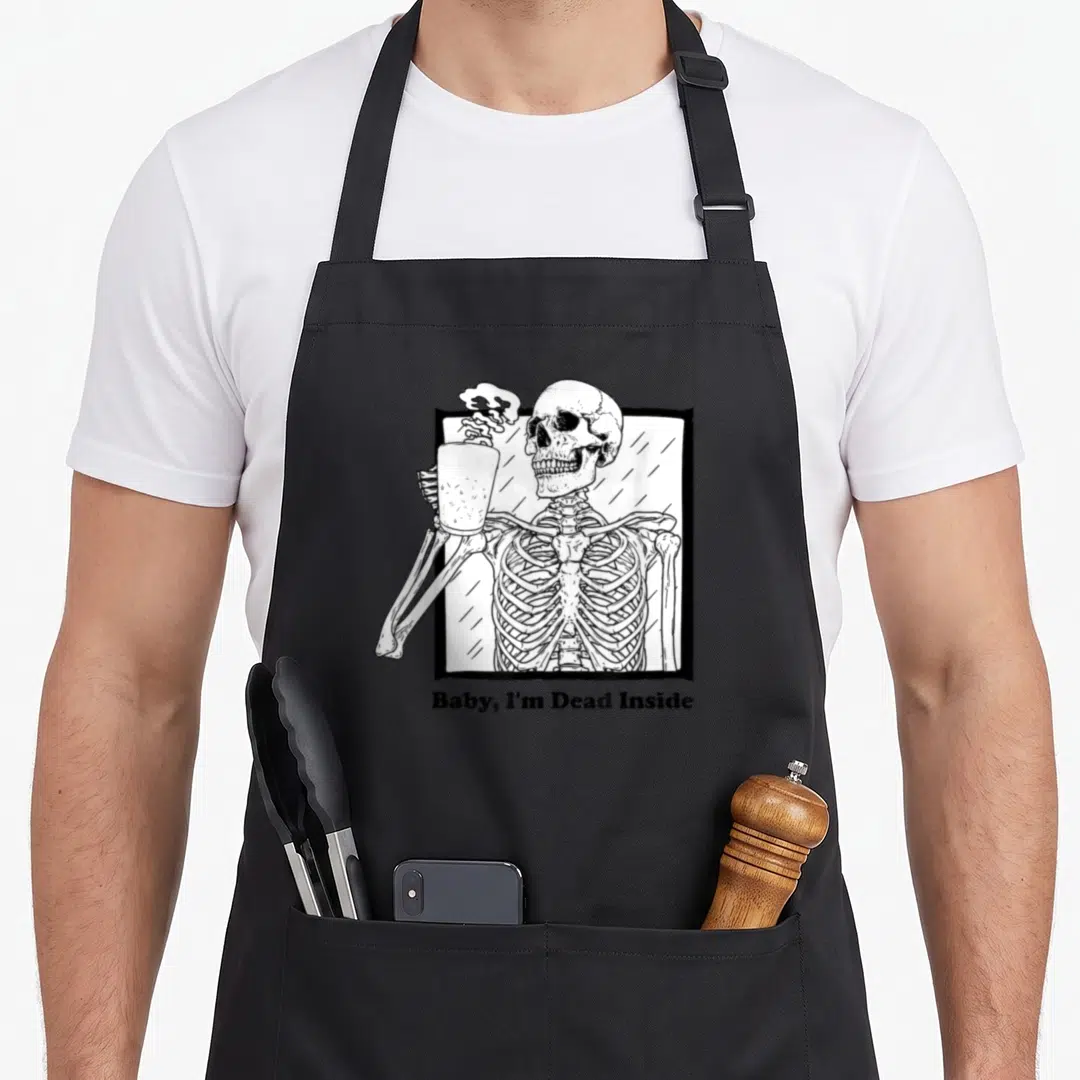 Ich goth apron - Skeleton holding steaming cup in white frame with text Baby I'm Dead Inside below — shown on a black cotton canvas apron against a white background
