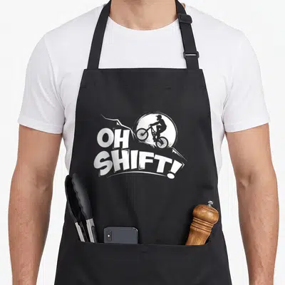 Shift bike bicycle apron - White OH SHIFT text and biker silhouette on black bib apron — shown on a black cotton canvas apron against a white background