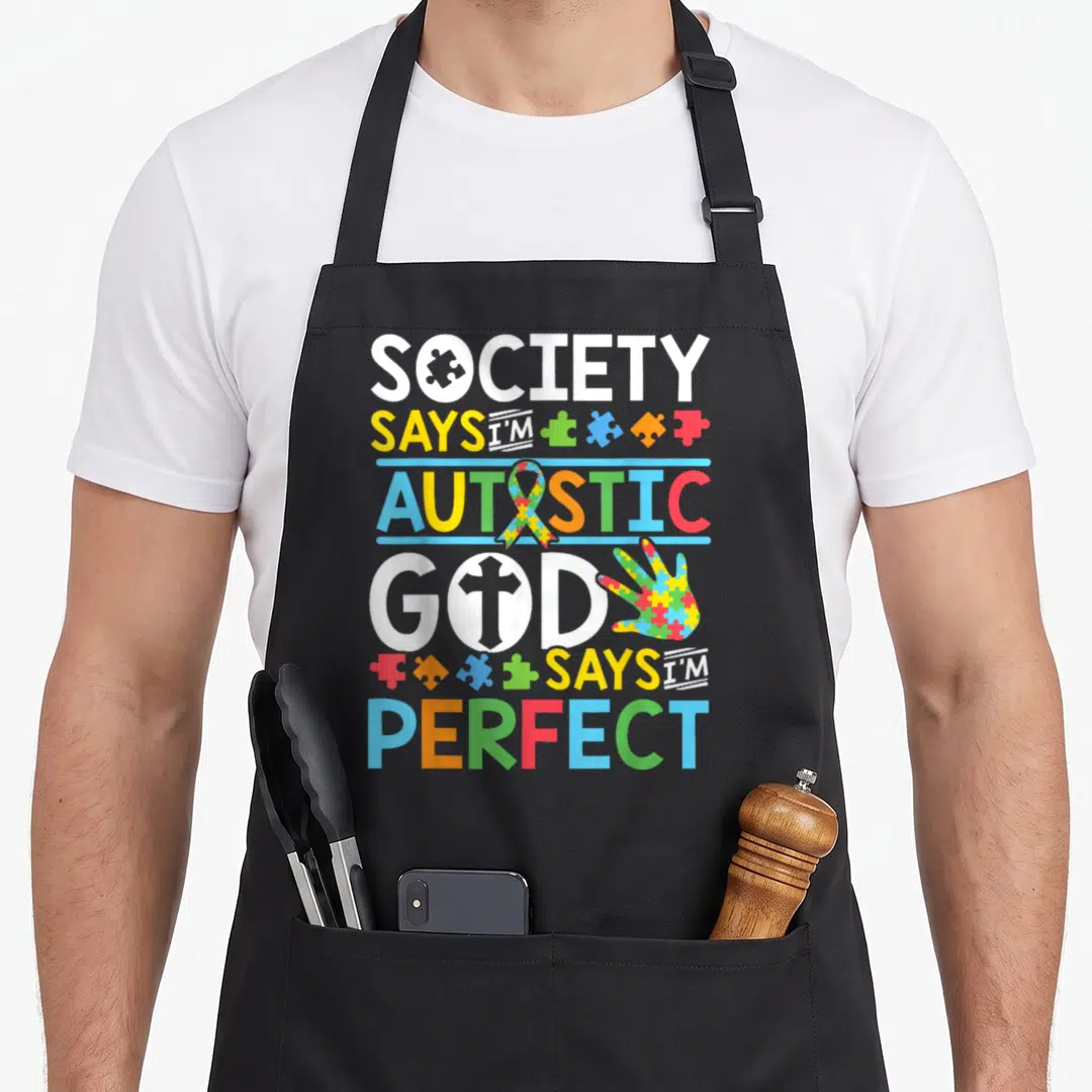 Society mom daughter apron - Stacked text with puzzle piece in O, ribbon, cross in O, puzzle-hand, scattered pieces — shown on a black cotton canvas apron against a white background