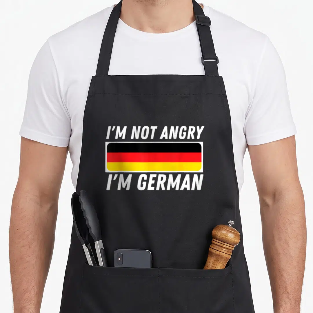 Angry german apron - I'M NOT ANGRY I'M GERMAN text above black red and yellow flag — shown on a black cotton canvas apron against a white background