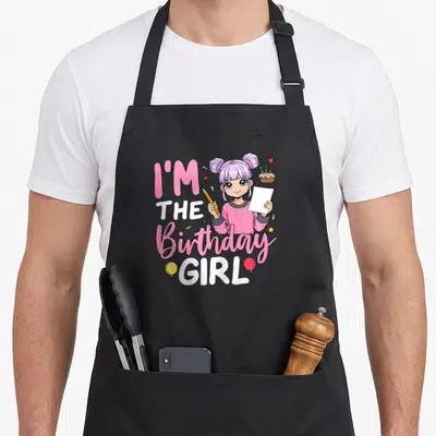 Sketching anime mom apron - Cartoon girl with purple hair holding pencil and paper, surrounded by I'M THE Birthday GIRL — shown on a black cotton canvas apron against a white background