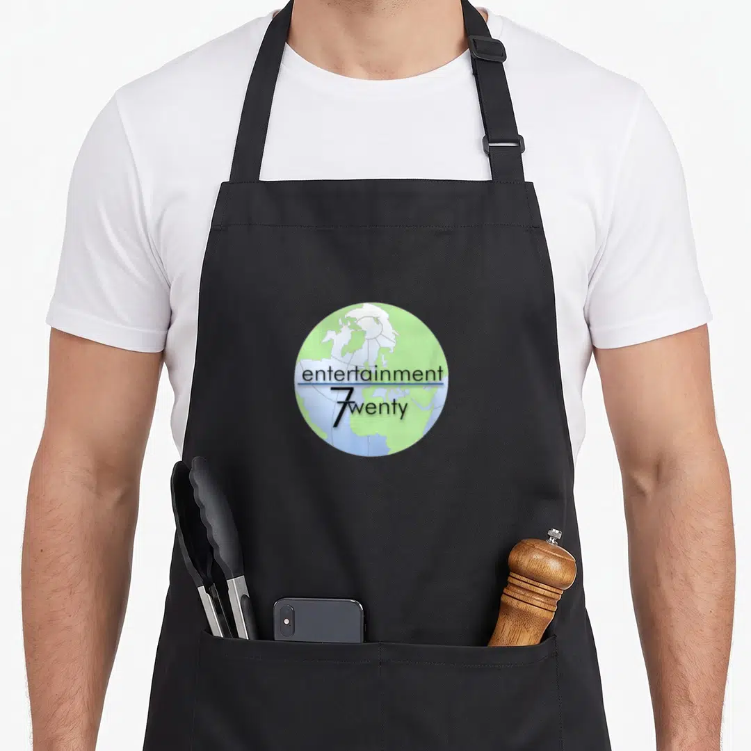 Nbc halloween apron - Green and blue globe illustration with stacked entertainment 7wenty text separated — shown on a black cotton canvas apron against a white background