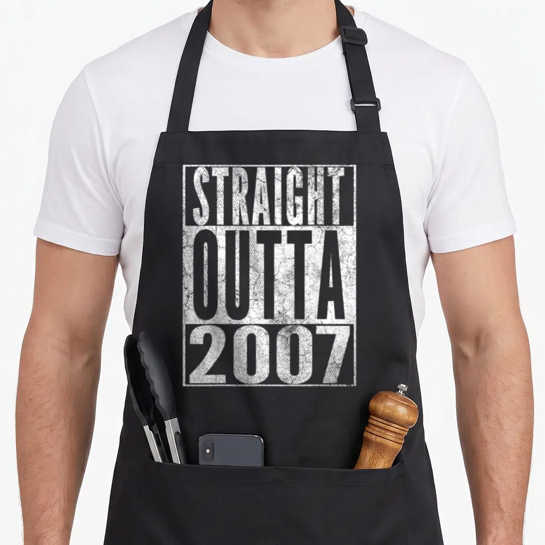 Straight outta 19th birthday apron - White STRAIGHT OUTTA 2007 typography in distressed font within rectangular border — shown on a black cotton canvas apron against a white background