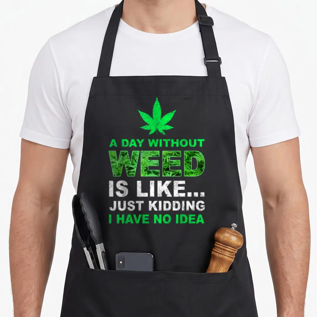 Weed pot apron - Green cannabis leaf above stacked text WEED filled with plant photo and distressed white lettering — shown on a black cotton canvas apron against a white background