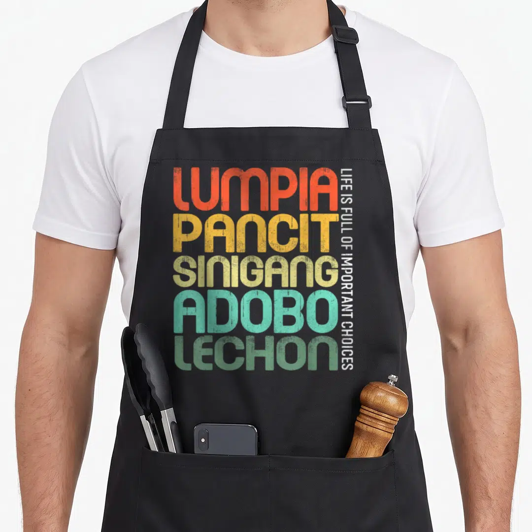 Filipino food aprons - Lumpia Pancit Sinigang Adobo Lechon stacked typography with vertical slogan Life Is Full — shown on a black cotton canvas apron against a white background