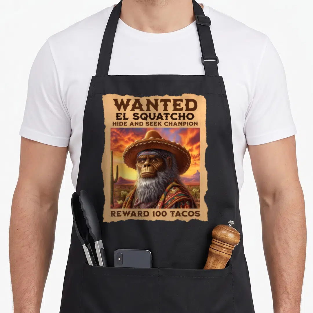 Wanted bigfoot apron - Weathered wanted poster showing El Squatcho in sombrero with 100 tacos reward text — shown on a black cotton canvas apron against a white background
