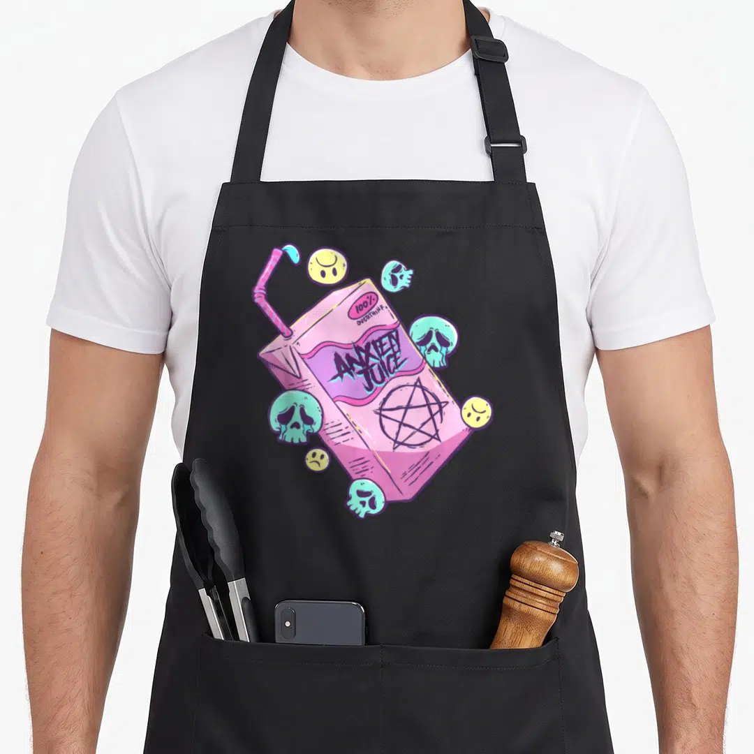Juice goth apron - Pink juice box with ANXIETY JUICE text, skulls, smiley faces, and a pentagram in pastel colors — shown on a black cotton canvas apron against a white background