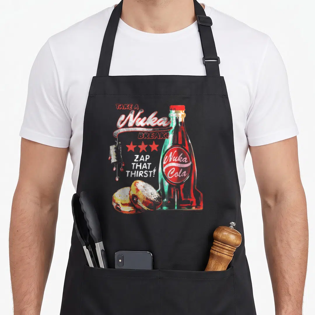 Nuka video game apron - Retro Nuka Cola bottle, three red stars, scattered text, and food items in red and teal — shown on a black cotton canvas apron against a white background