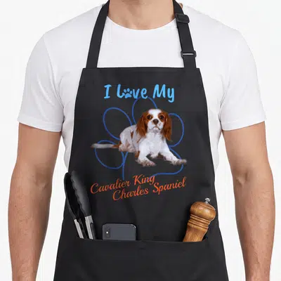 Dog paw king apron - Cartoon spaniel in blue flower outline with I Love My Cavalier King Charles Spaniel text — shown on a black cotton canvas apron against a white background