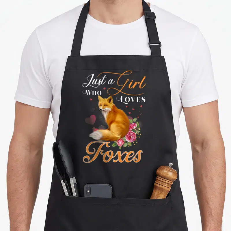 Coyote fox aprons - Realistic orange fox with pink roses and Just a Girl Who Loves Foxes text — shown on a black cotton canvas apron against a white background