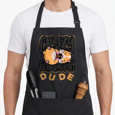 Guinea dude apron - Cartoon guinea pig between CRAZY GUINEA PIG DUDE text with orange outlines — shown on a black cotton canvas apron against a white background