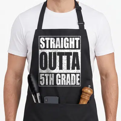 Outta fifth apron - White distressed text STRAIGHT OUTTA 5TH GRADE stacked in a rectangular border — shown on a black cotton canvas apron against a white background