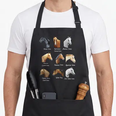 Breed equestrian horse apron - Nine horse heads in a grid with script names Friesian, Arabian, Appaloosa, Welsh Pony — shown on a black cotton canvas apron against a white background