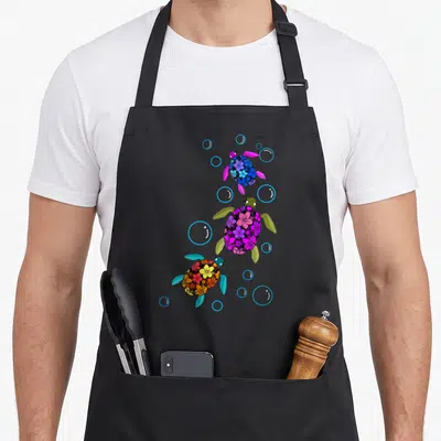 Sea tropical print aprons - Three floral sea turtles swimming diagonally with blue bubbles in blue purple orange — shown on a black cotton canvas apron against a white background