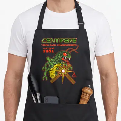 Atari centipede apron - Green centipede over starburst with 1981 Las Vegas video game championships text — shown on a black cotton canvas apron against a white background