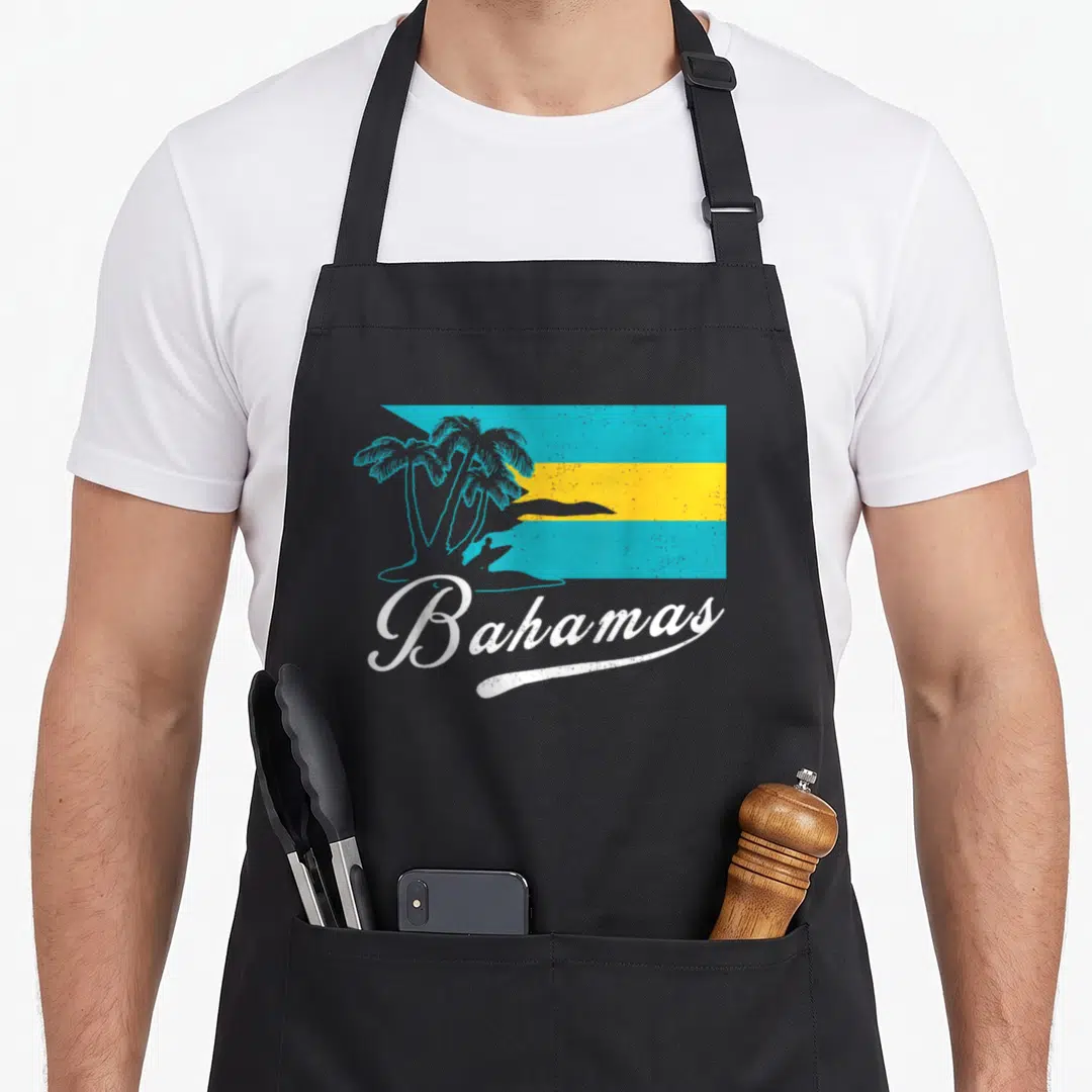 Funny proud bahamian apron - Retro Bahamas flag with palm trees and white script text in turquoise and yellow — shown on a black cotton canvas apron against a white background