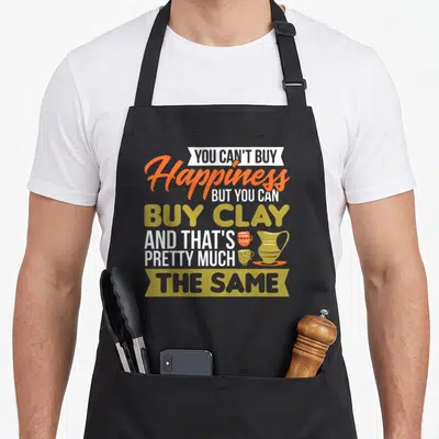 Happiness maker apron - Typography art reading buy clay with three pottery vessels in orange and olive green — shown on a black cotton canvas apron against a white background