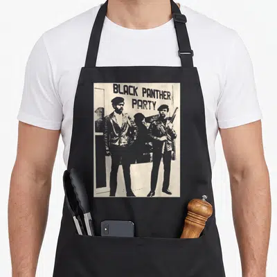 Bpp black history apron - Distressed beige print of Black Panther Party text above two standing men, one holding a rifle — shown on a black cotton canvas apron against a white background