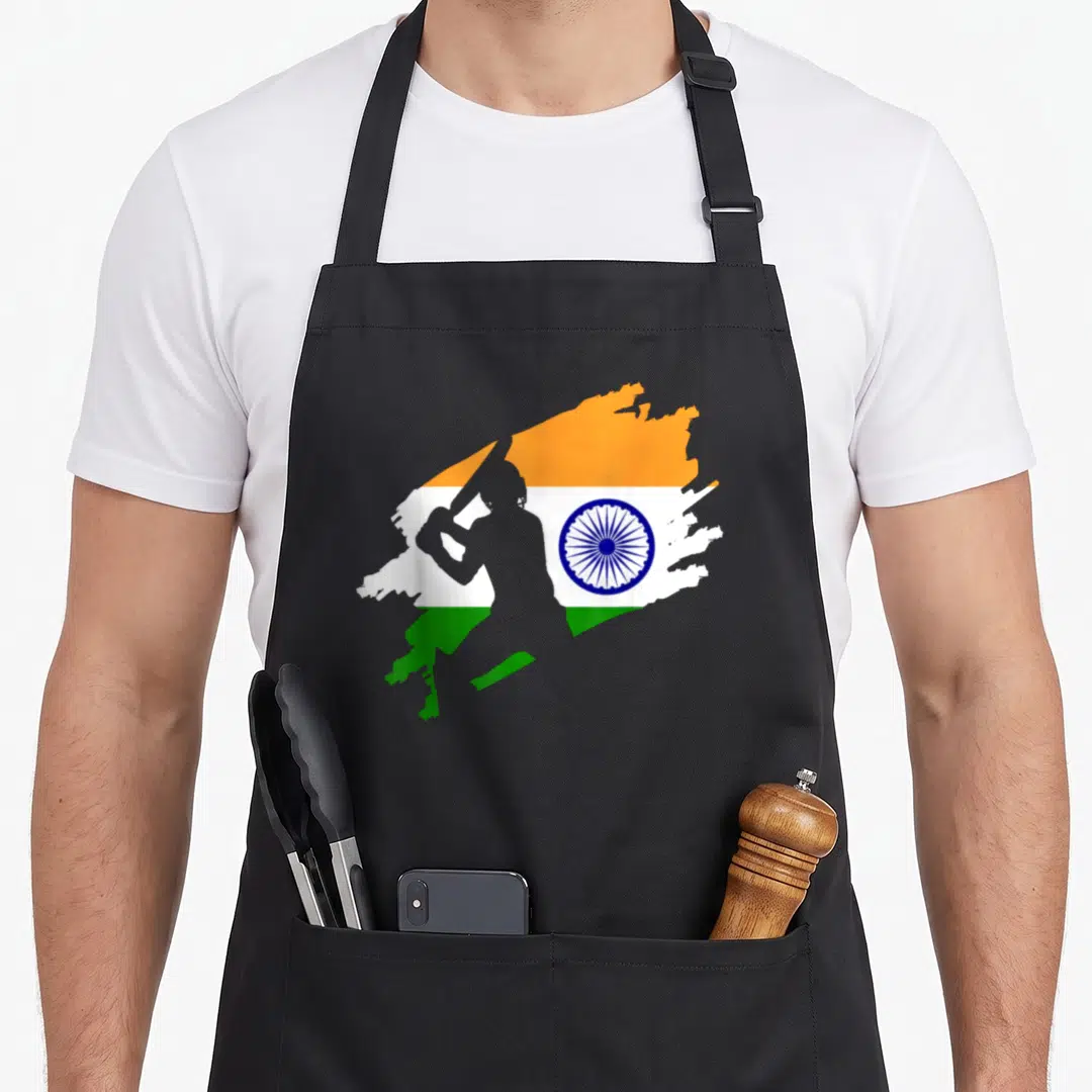 Patriotic cricket apron - Cricketer silhouette over orange white green and blue brush stroke flag with blue wheel — shown on a black cotton canvas apron against a white background