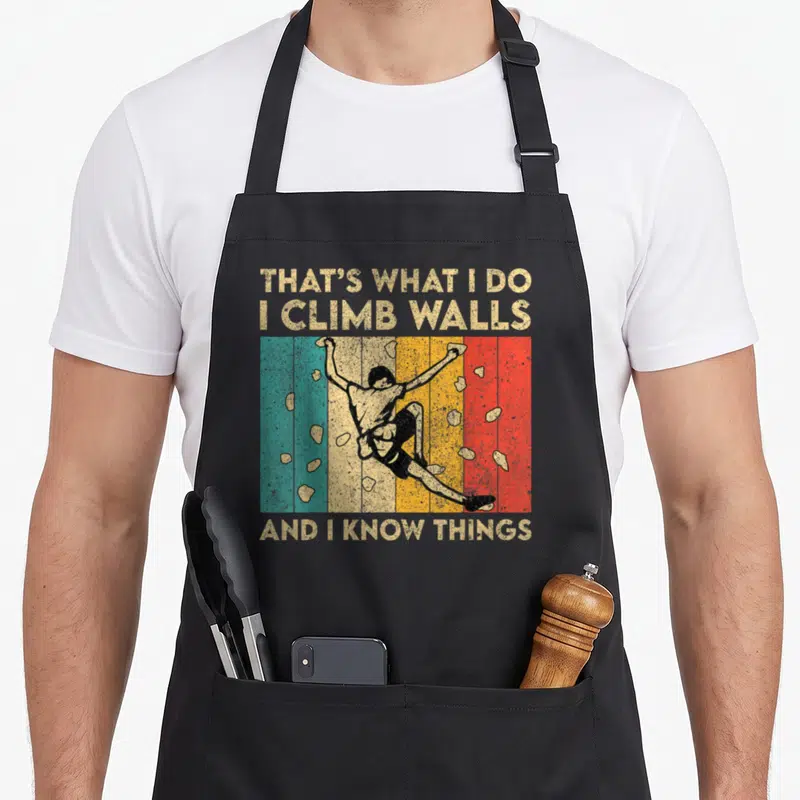 Climb bouldering apron - Retro climber on teal, beige, yellow, orange, and red stripes with scattered holds — shown on a black cotton canvas apron against a white background