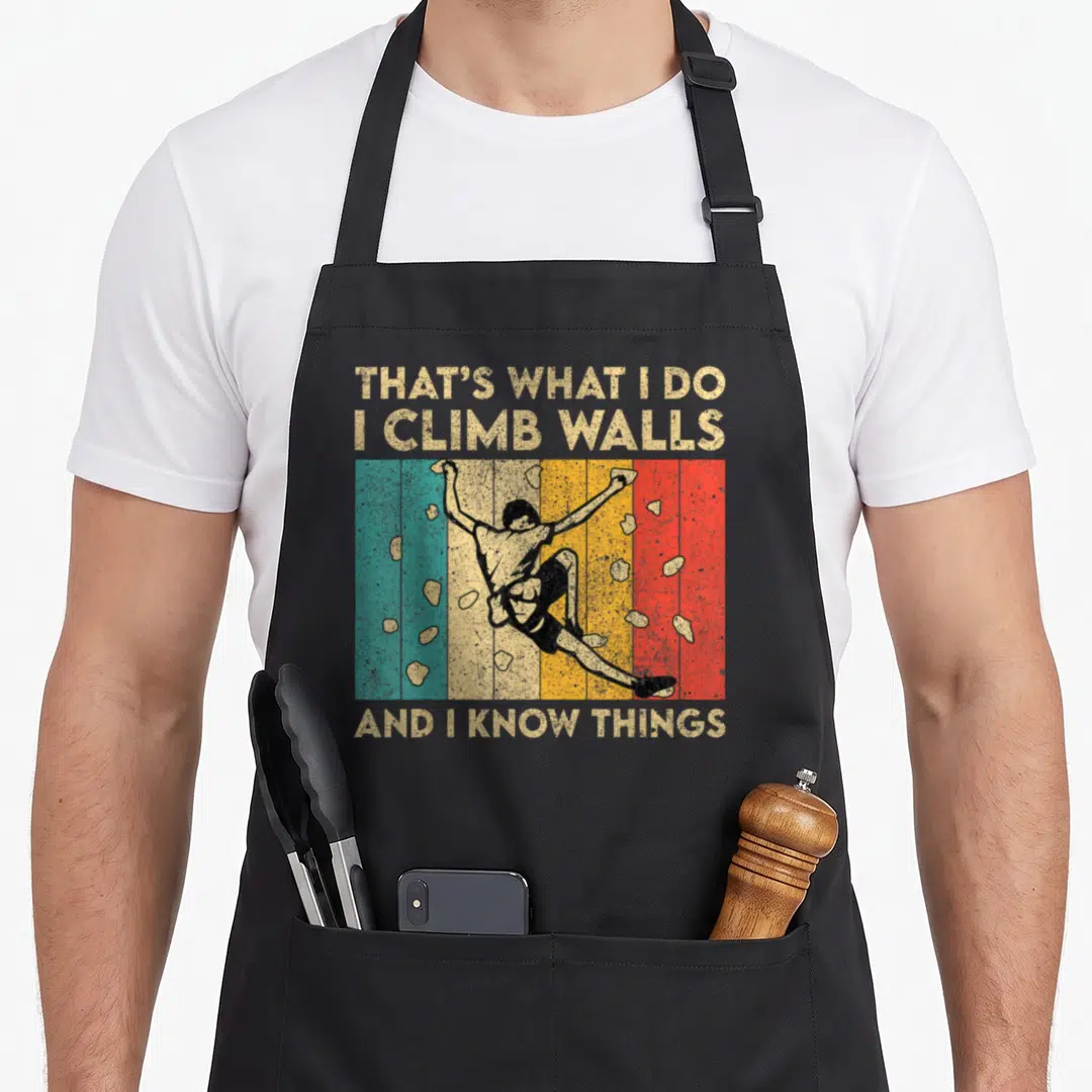 Climb bouldering apron - Retro climber on teal, beige, yellow, orange, and red stripes with scattered holds — shown on a black cotton canvas apron against a white background