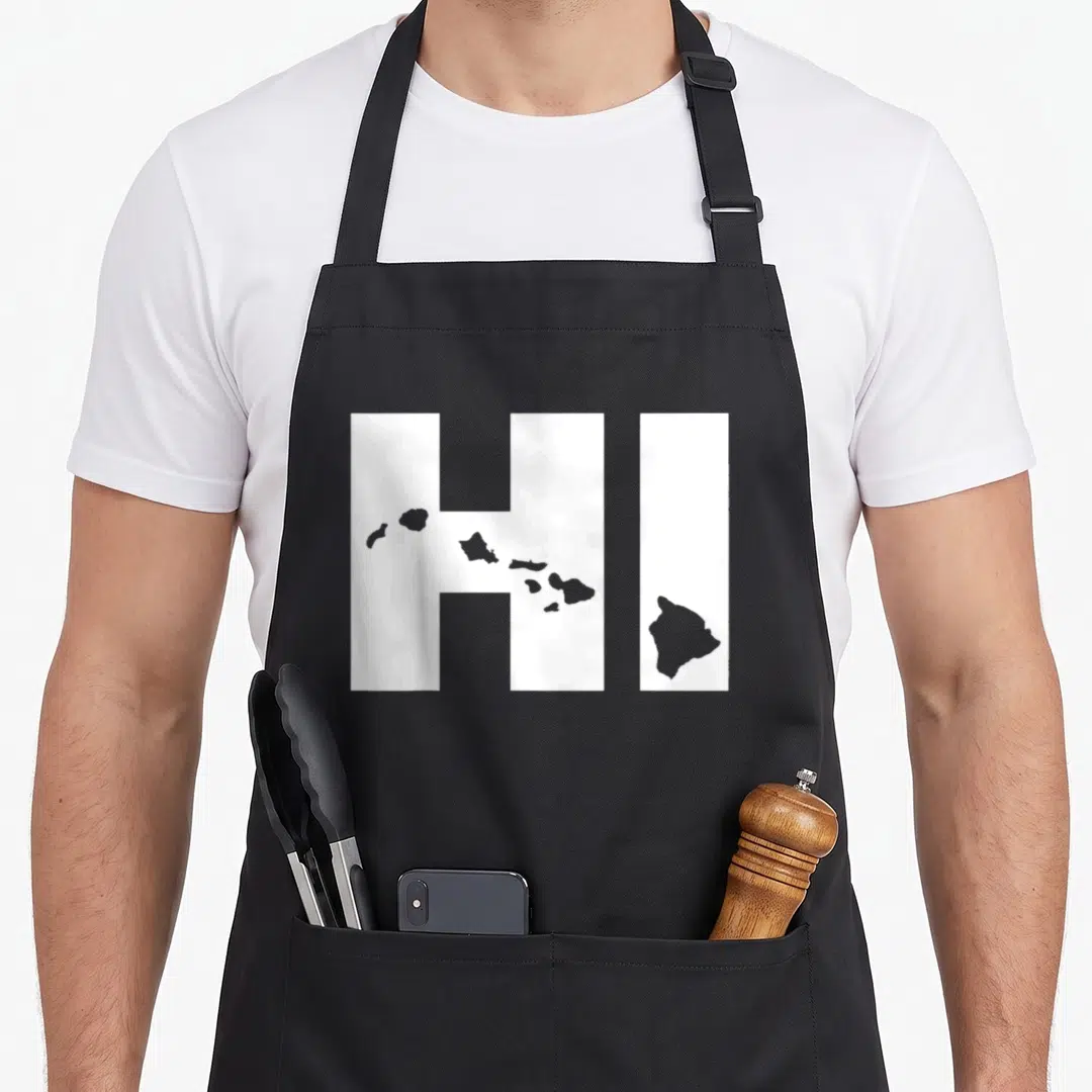 Map hawaii girl apron - White HI letters with grey Hawaiian island silhouettes overlaid across the front panel — shown on a black cotton canvas apron against a white background