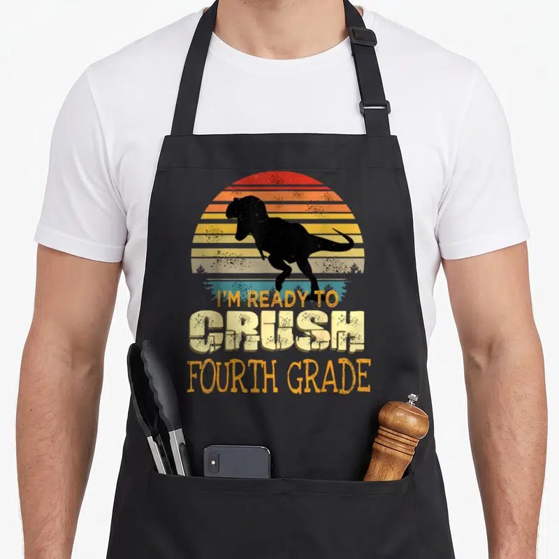 Grade dinosaur apron - Black T-Rex silhouette over retro striped sun with I'M READY TO CRUSH FOURTH GRADE text — shown on a black cotton canvas apron against a white background