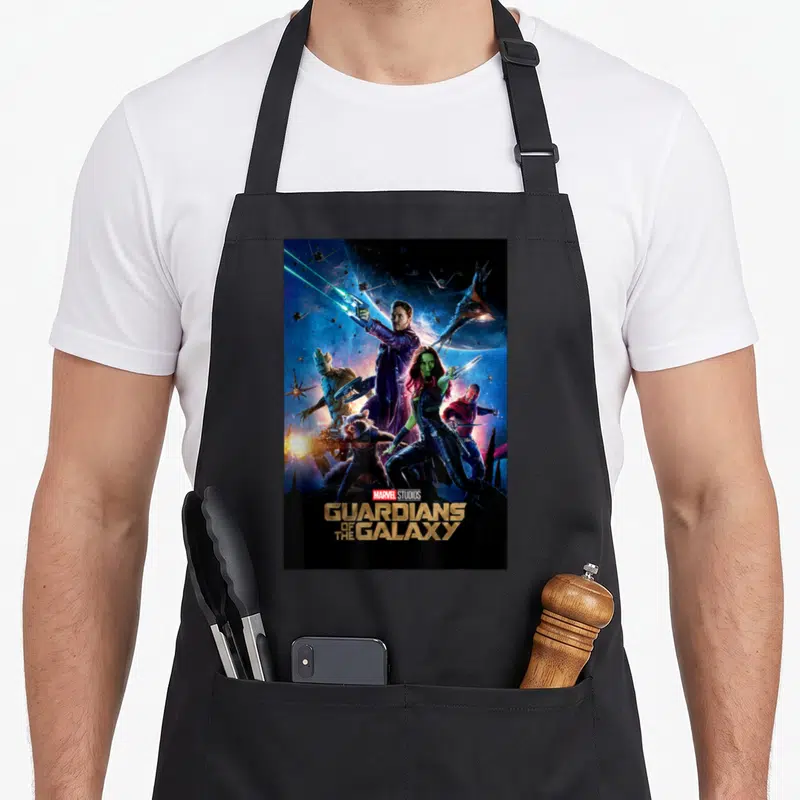 Studio galaxies apron - Guardians of the Galaxy photo print with stacked gold title text and space background — shown on a black cotton canvas apron against a white background