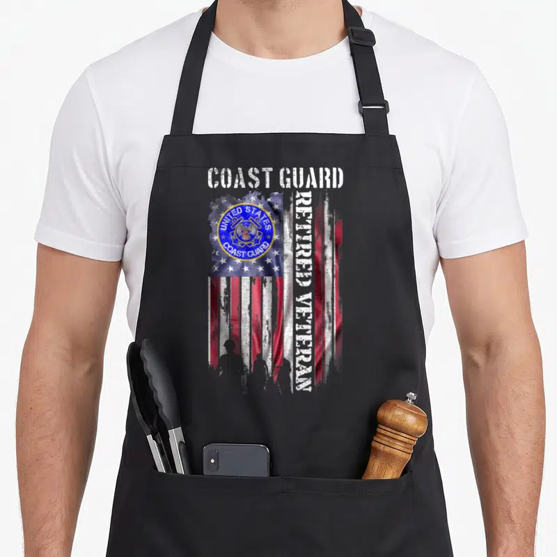 Guard american flag apron - Distressed US Coast Guard emblem on flag with vertical retired veteran text — shown on a black cotton canvas apron against a white background