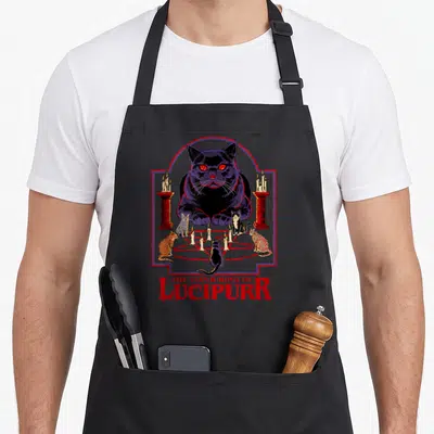 Conjuring steven rhodes apron - Black cat behind red pentagram with four smaller cats and dripping text — shown on a black cotton canvas apron against a white background