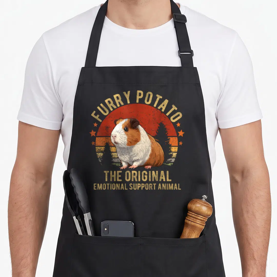 Guinea potato apron - Retro guinea pig illustration with FURRY POTATO text and sunset background — shown on a black cotton canvas apron against a white background